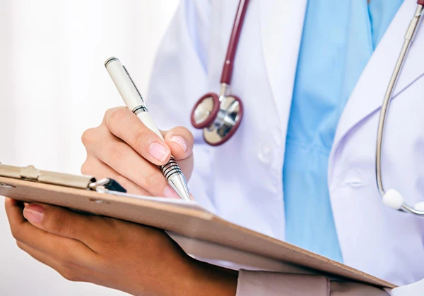 Professionnel de santé rédigeant un dossier médical pour l'aide aux démarches de santé et de handicap par SOCIALP