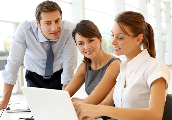 Équipe professionnelle échangeant autour d'un ordinateur pour l'accompagnement social au travail et le reclassement professionnel par SOCIALP